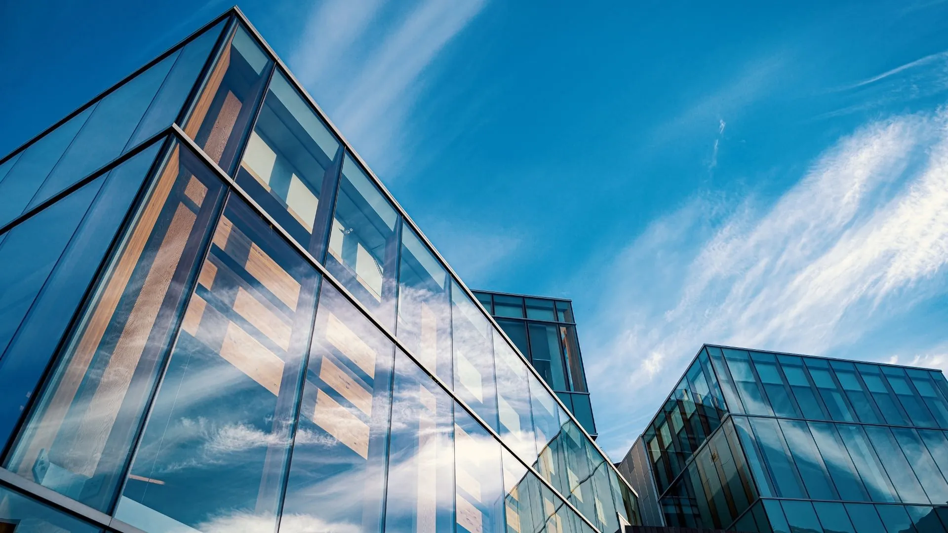 Glass building facade reflecting sky and clouds